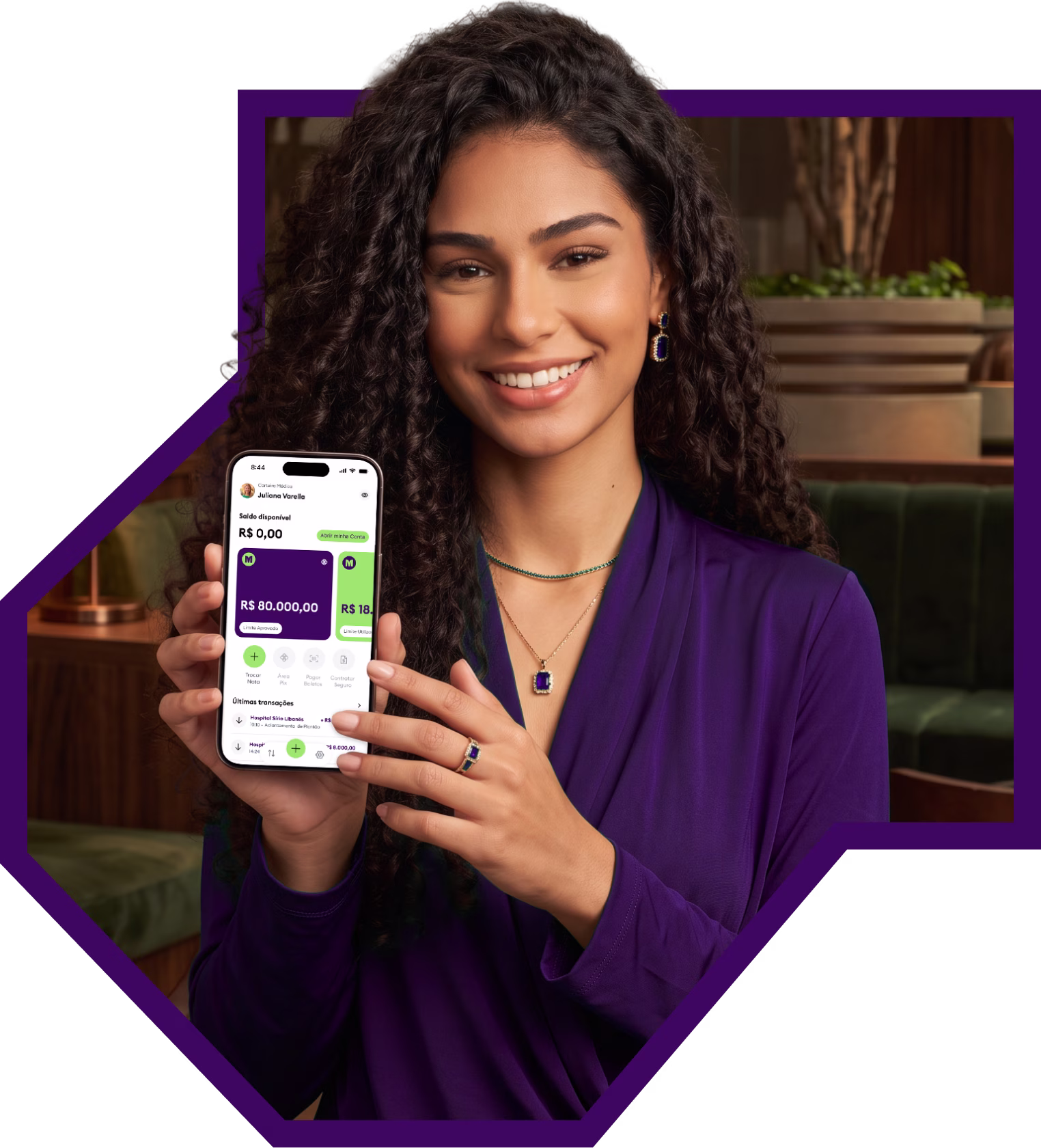 Médica sorrindo segurando o celular com o app da Medcred aberto