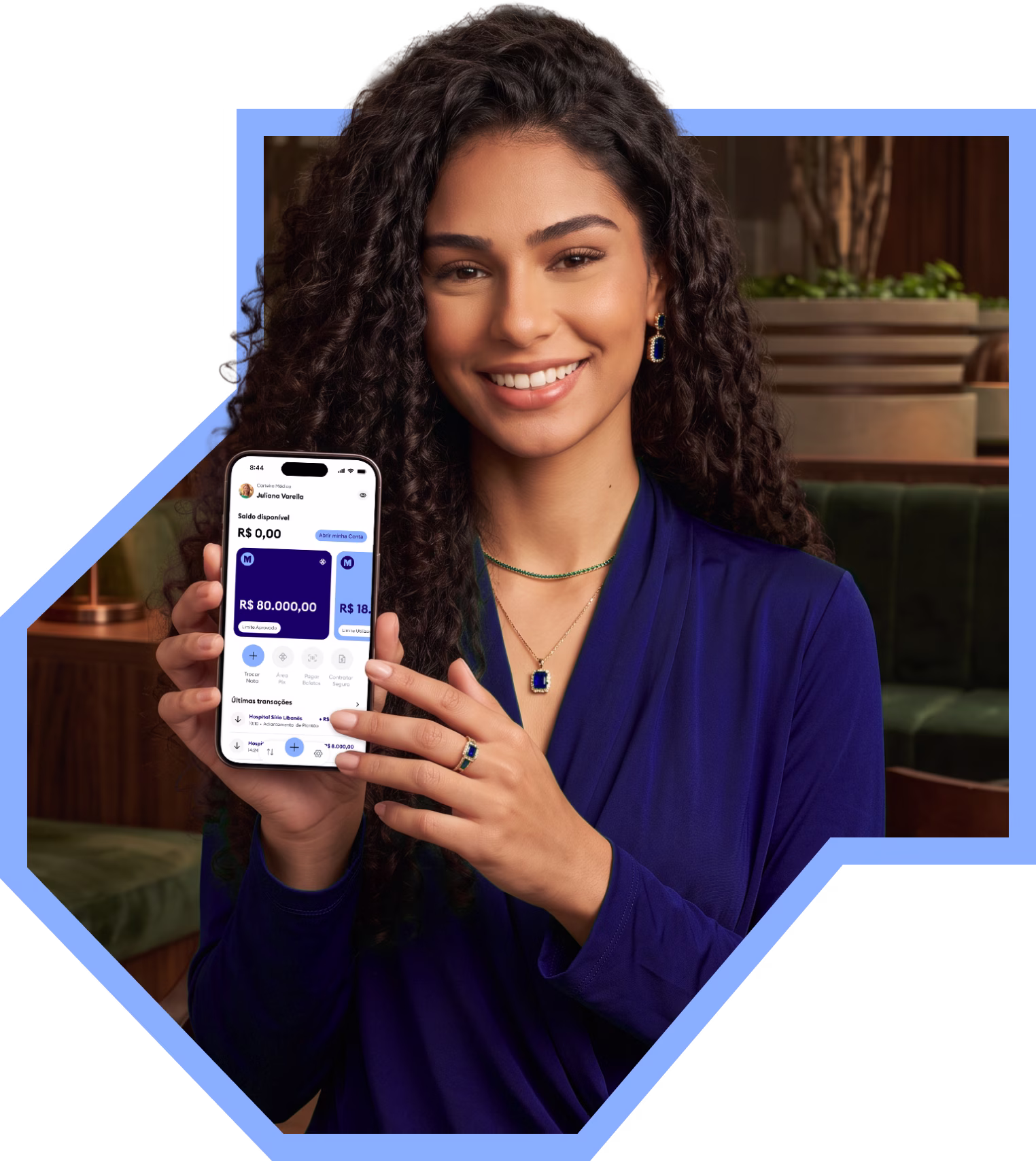 Médica sorrindo segurando o celular com o app da Medcred aberto